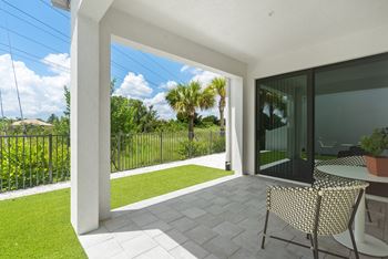 a patio with two chairs and a table and a lawn at Odyssey, Florida, 33905